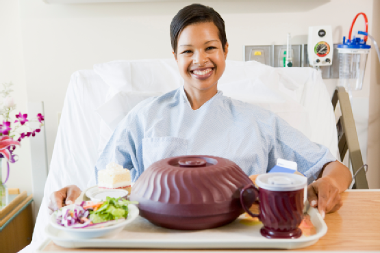 Woman Sitting In Hospital Bed With A Tray Of Food