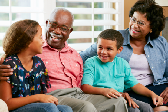 Grandparents With Grandchildren Sitting On Sofa And Talking